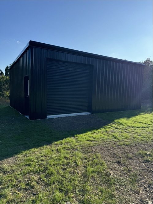 Black metal shop with roll-up door, Canyon Lake TX